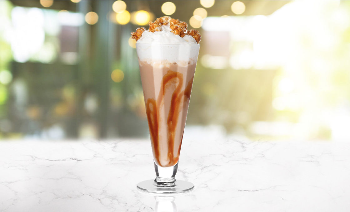 A glass of Iced Popcorn Boozy Frappe on a transparent background