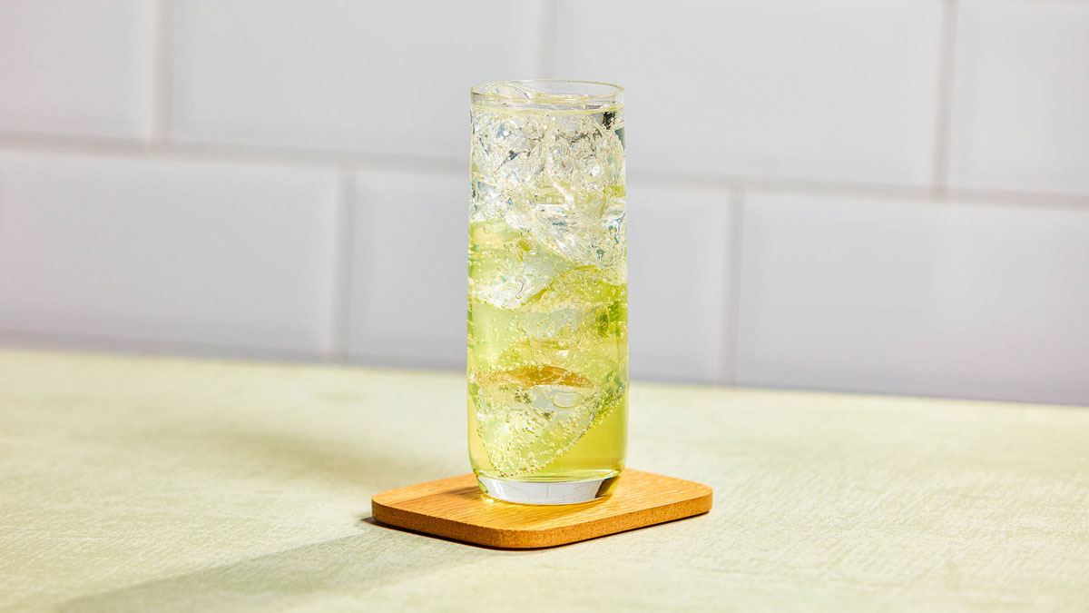 Glass of Apple fizz against a white tile wall