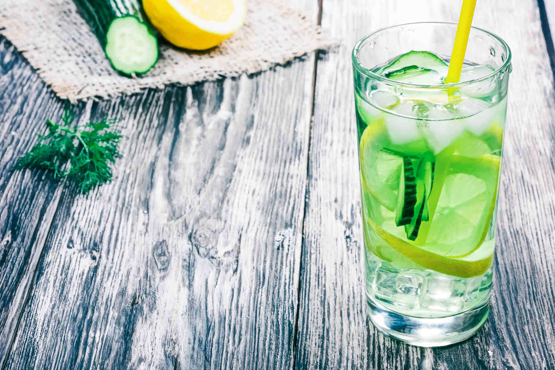 Glass of Green Dream on a wooden table with cucumber and lemon on a mat