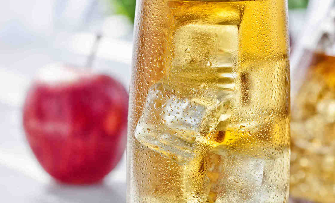 A glass of American pie with an apple in the background