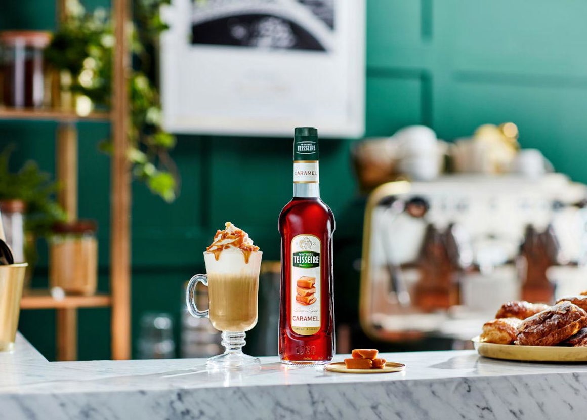 bottle of caramel syrup on a table with a baked goods