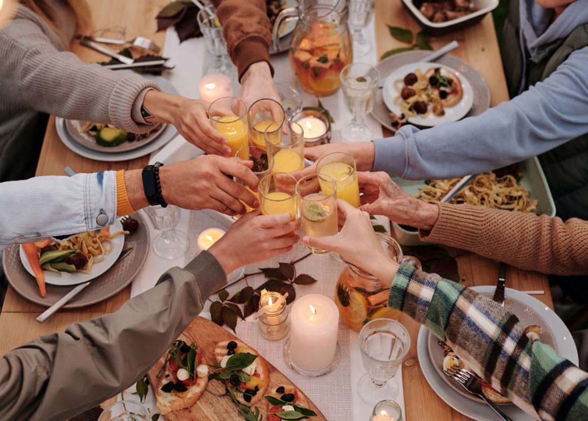 A group of people clinking glasses over a table of food