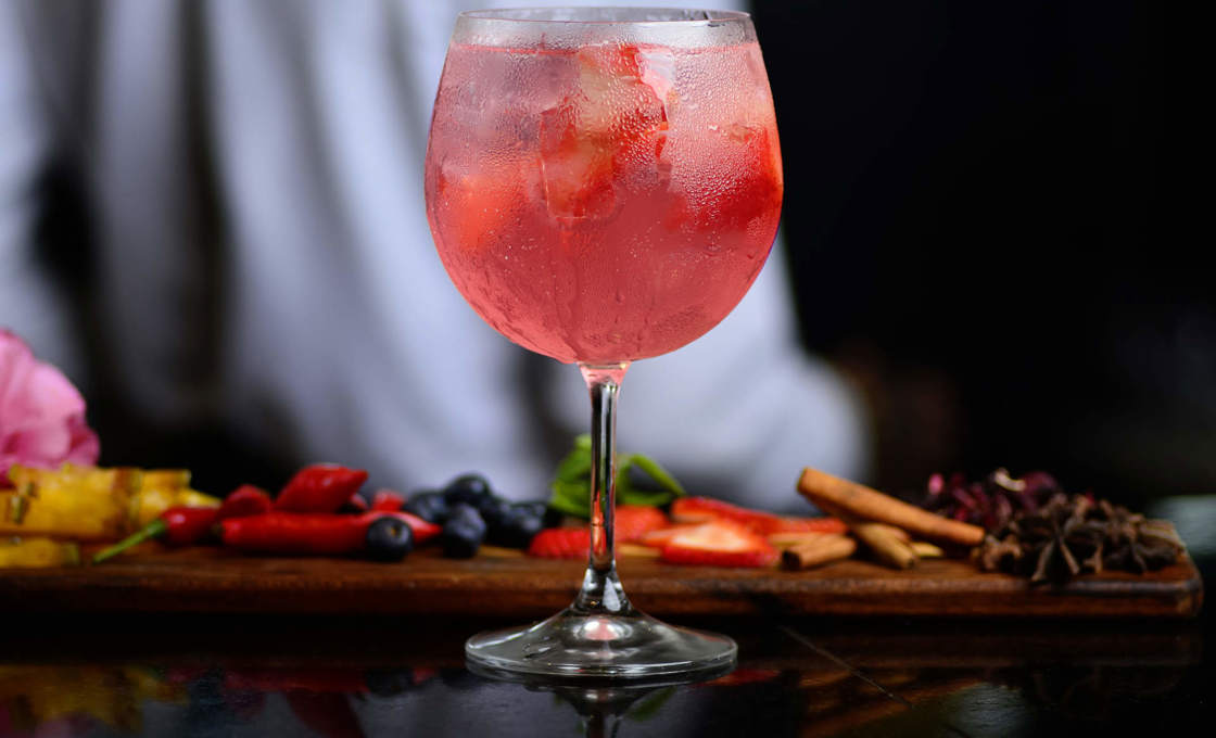 Fruity Vino in a glass beside spices on a dark bar