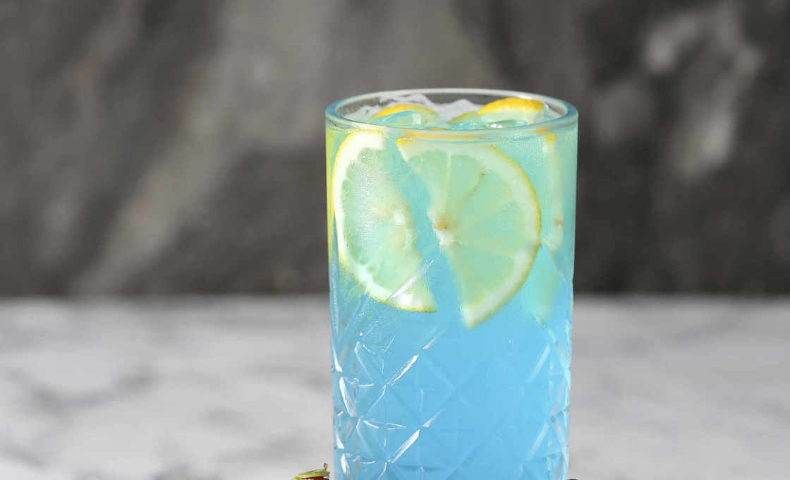 Glass of Blu Tonic in a crude wooden tray with strawberries and grapes