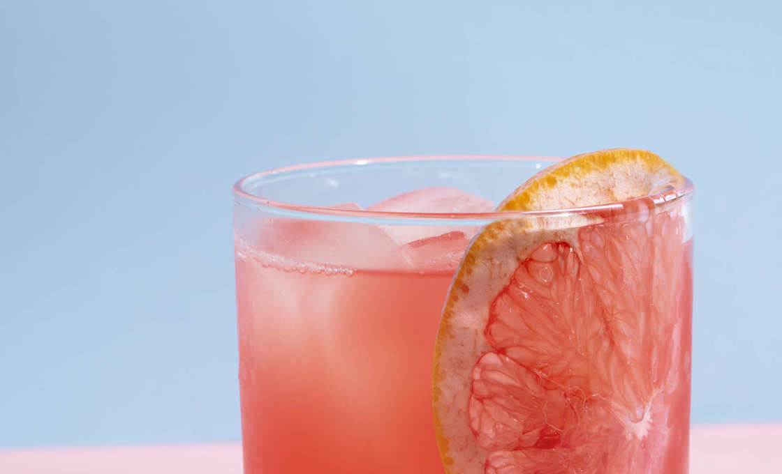 A glass of Pomme Peach on a pink table
