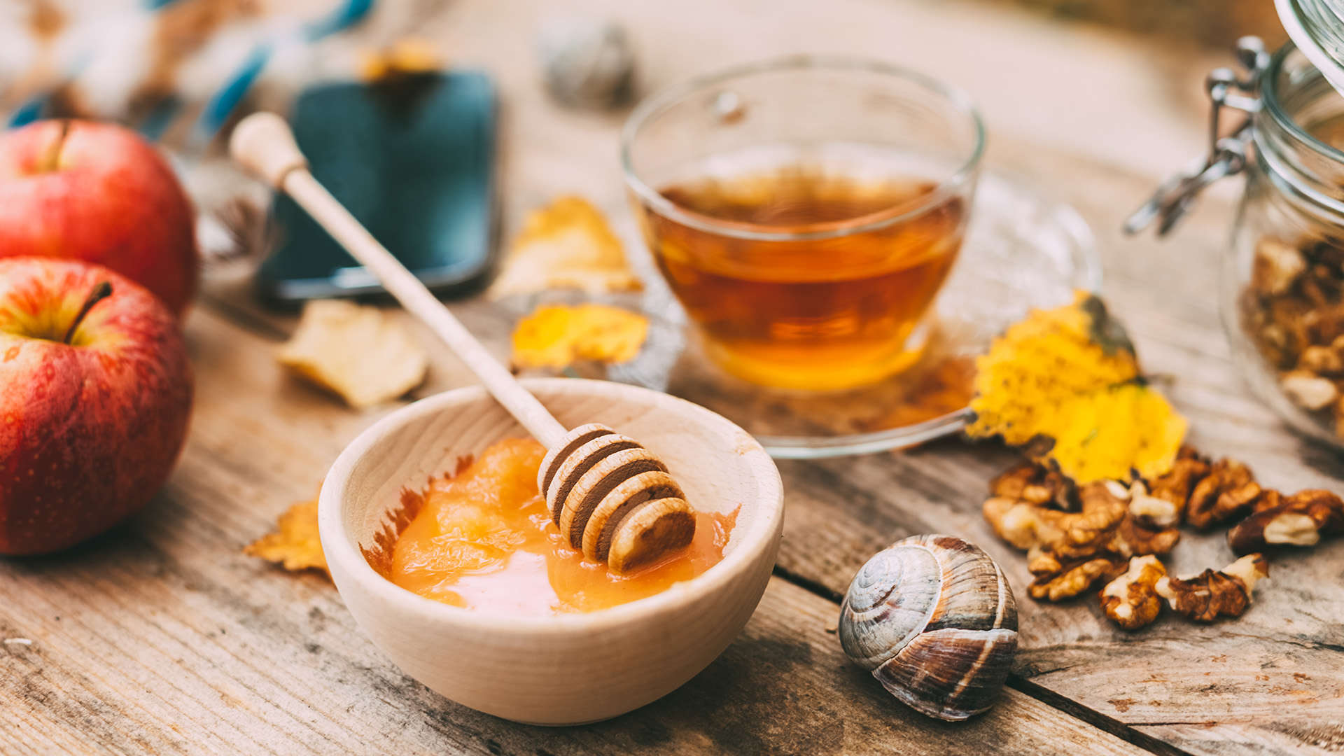 Honey, apples and a glass of tea on a rustic wooden table