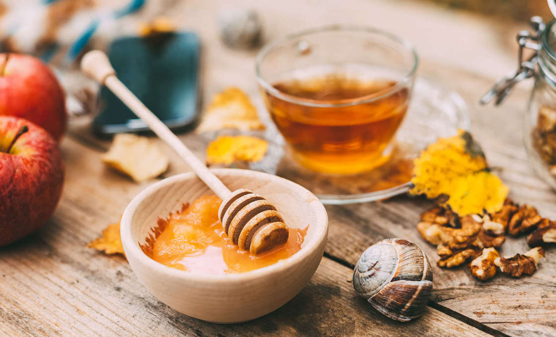 Honey, apples and a glass of tea on a rustic wooden table