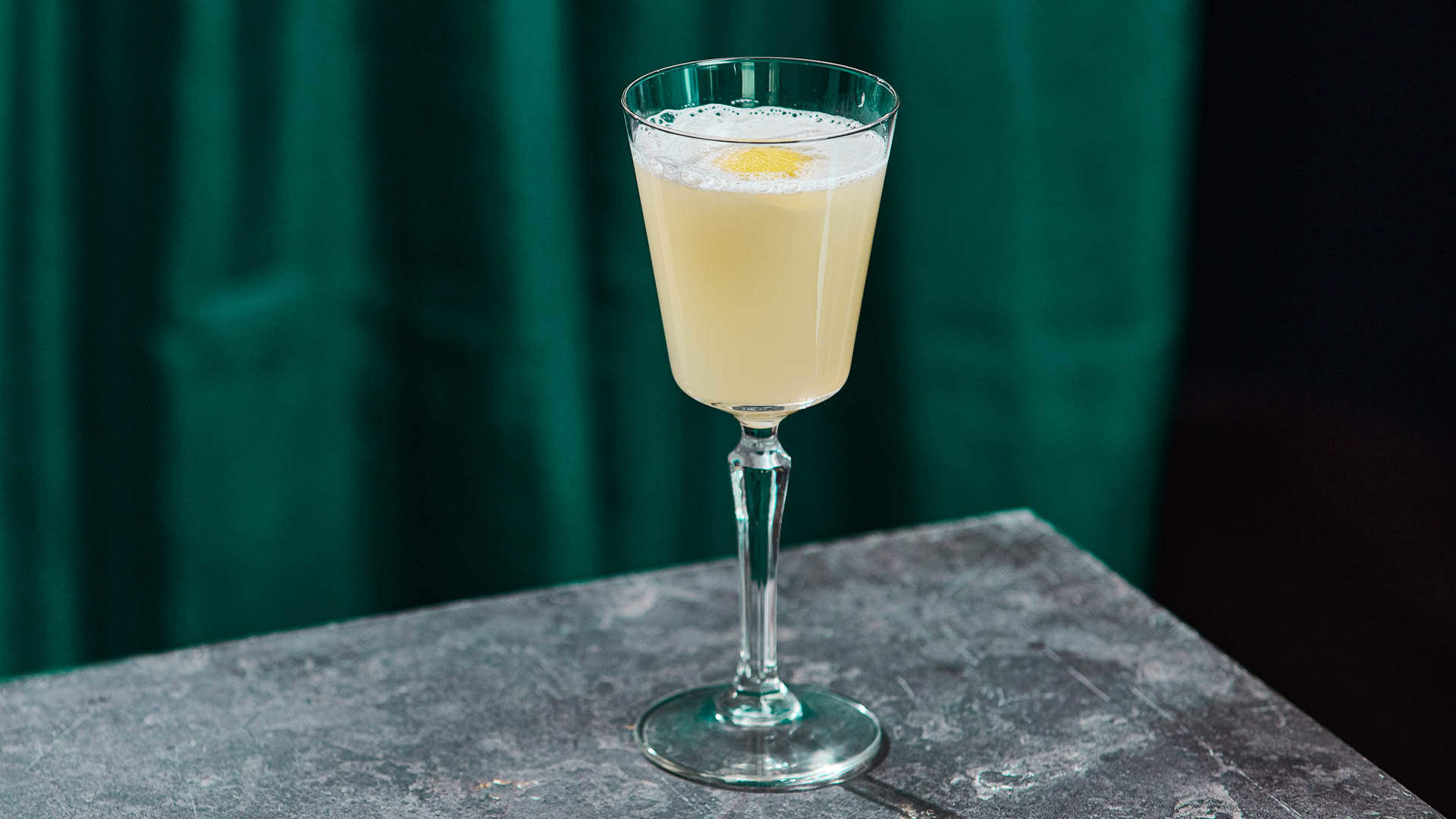 A glass of elderflower martini on the edge of a bar surface