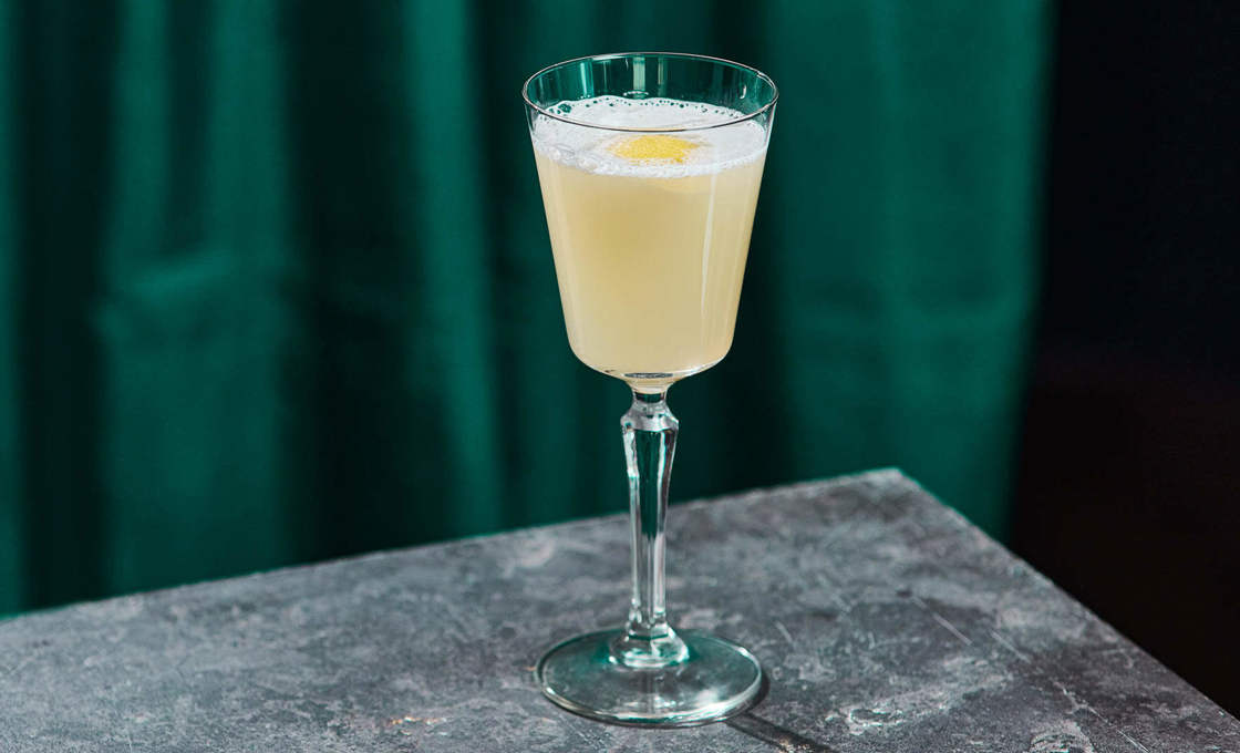 A glass of elderflower martini on the edge of a bar surface