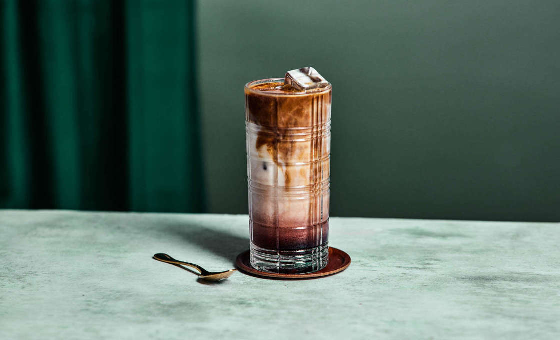 A glass of Dazzleberry iced latte with spoon and mat