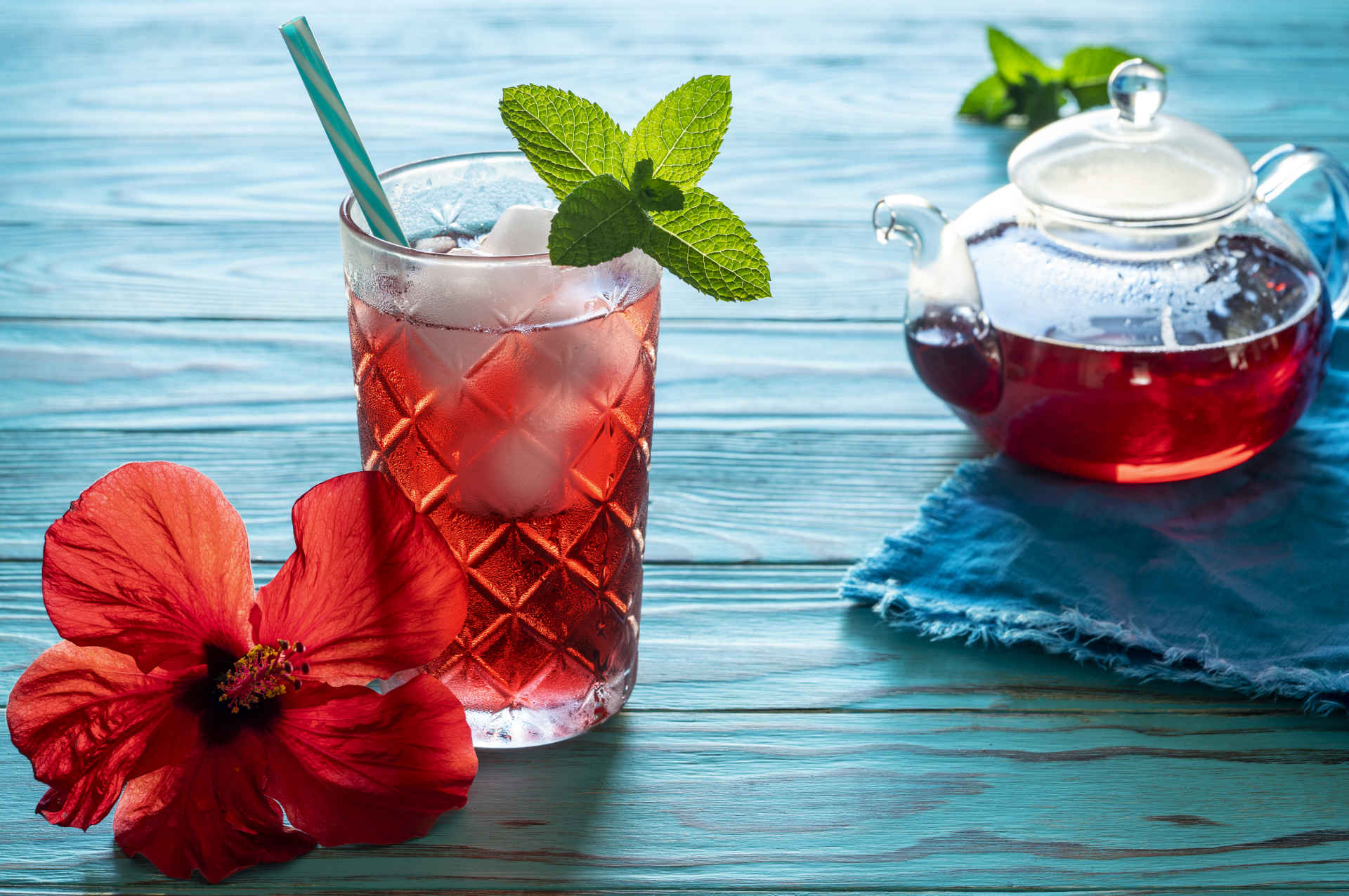 A pot and glass of Caribbean tea on a blue wooden table