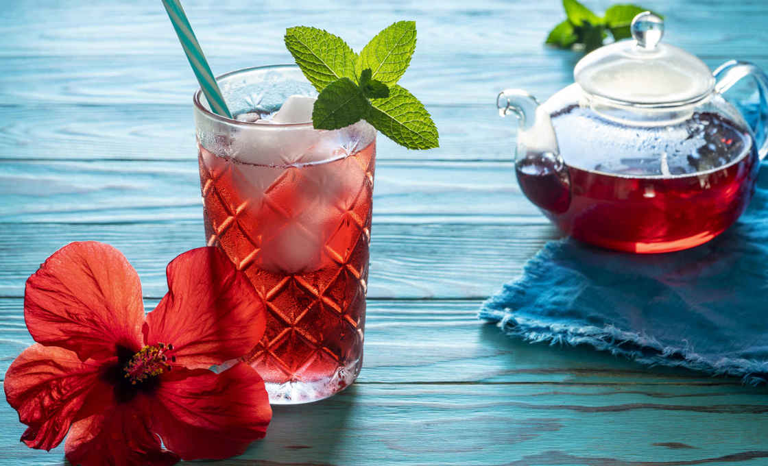 A pot and glass of Caribbean tea on a blue wooden table