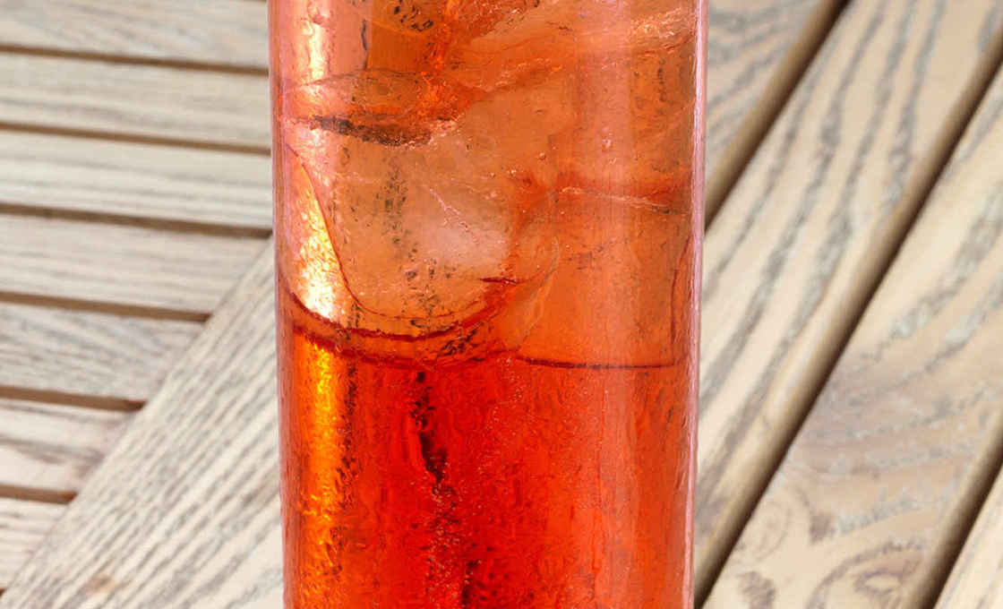 Tall glass of Cherry & Peach Sparkler on a wooden table