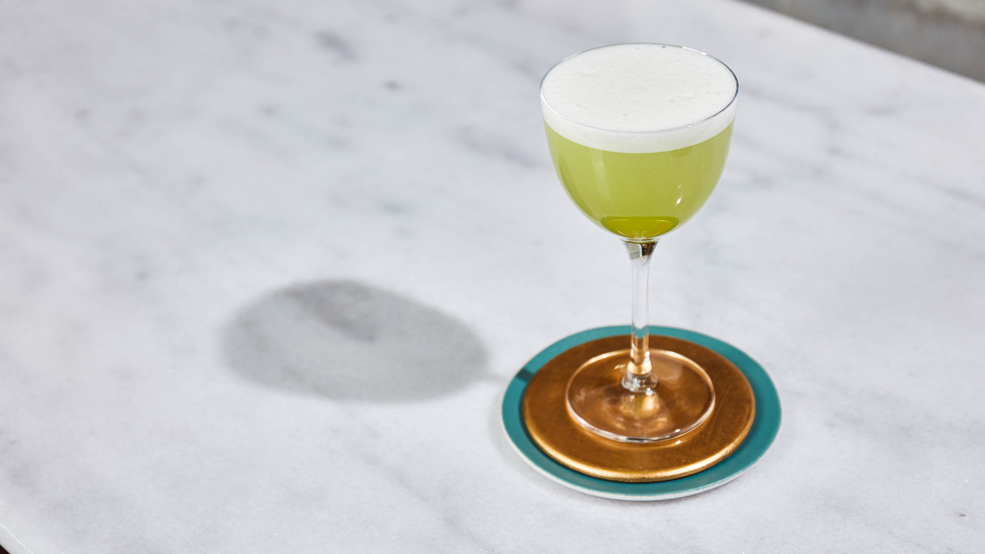 Glass of So Blu sitting on a metal mat on a marble surface