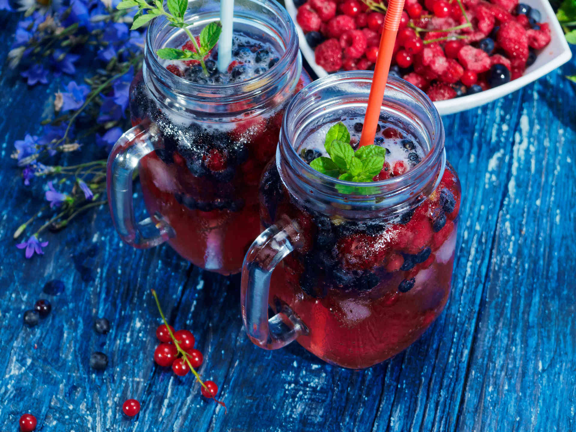 Two glasses of Blueberry Iced Tea on a table with blueberries in a bowl