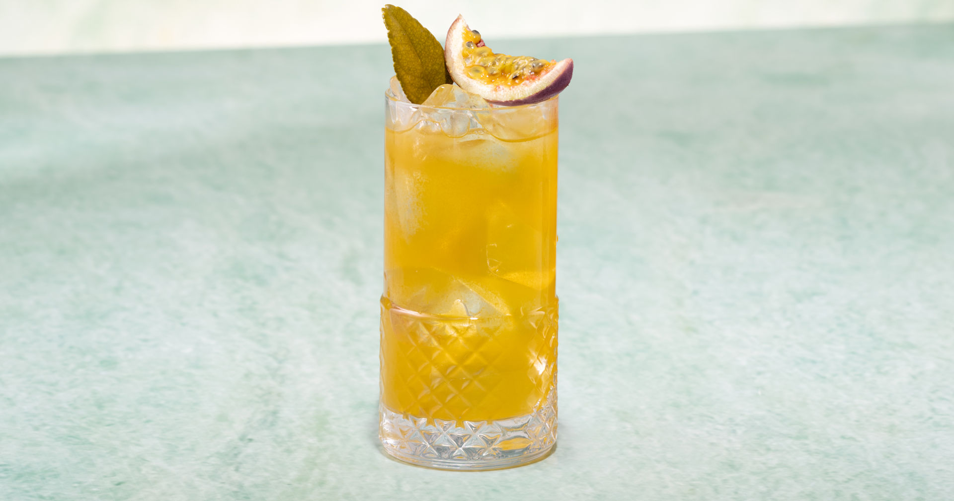 Glass of Summer Passion Fruit Iced Tea on a light green surface