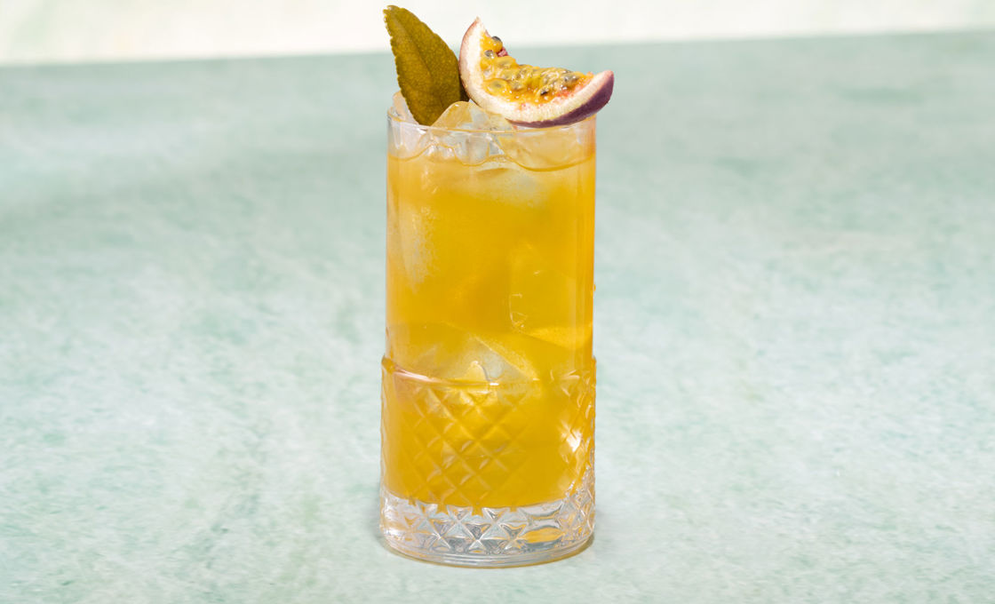 Glass of Summer Passion Fruit Iced Tea on a light green surface