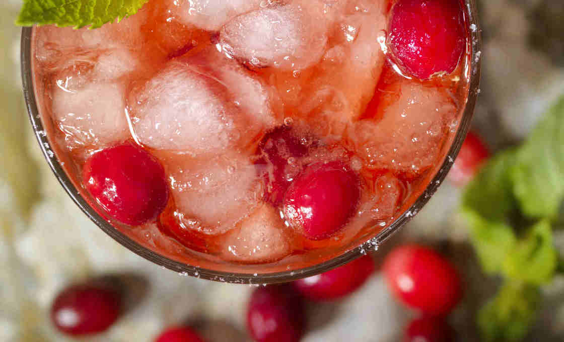 Top down view of a glass of cranberry refresher with loose cranberries