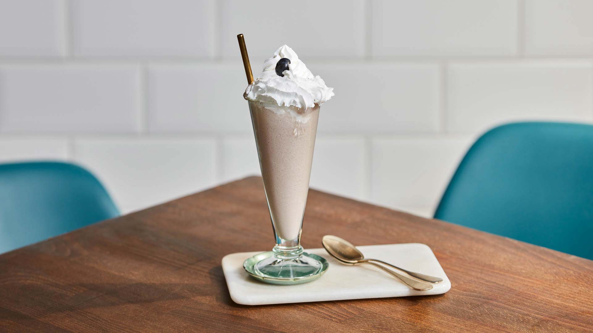 Glass of Violet Milkshake on a table with chairs