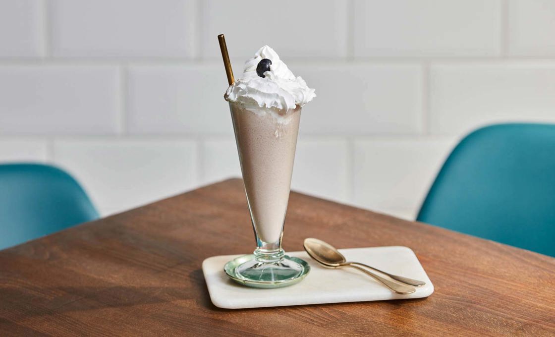 Glass of Violet Milkshake on a table with chairs
