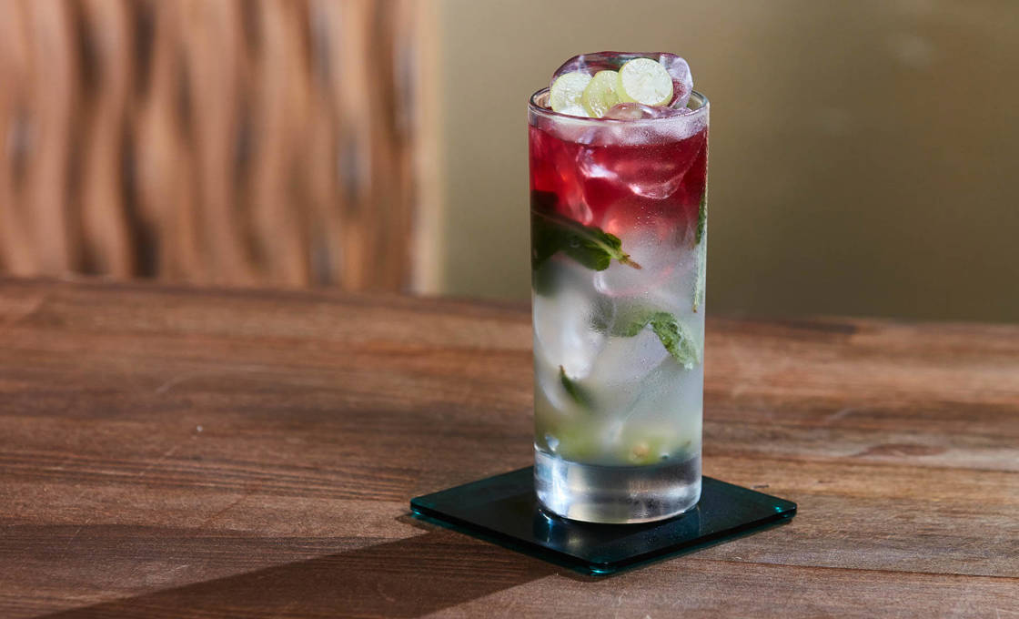A glass of lavender fruit cooler on a coaster