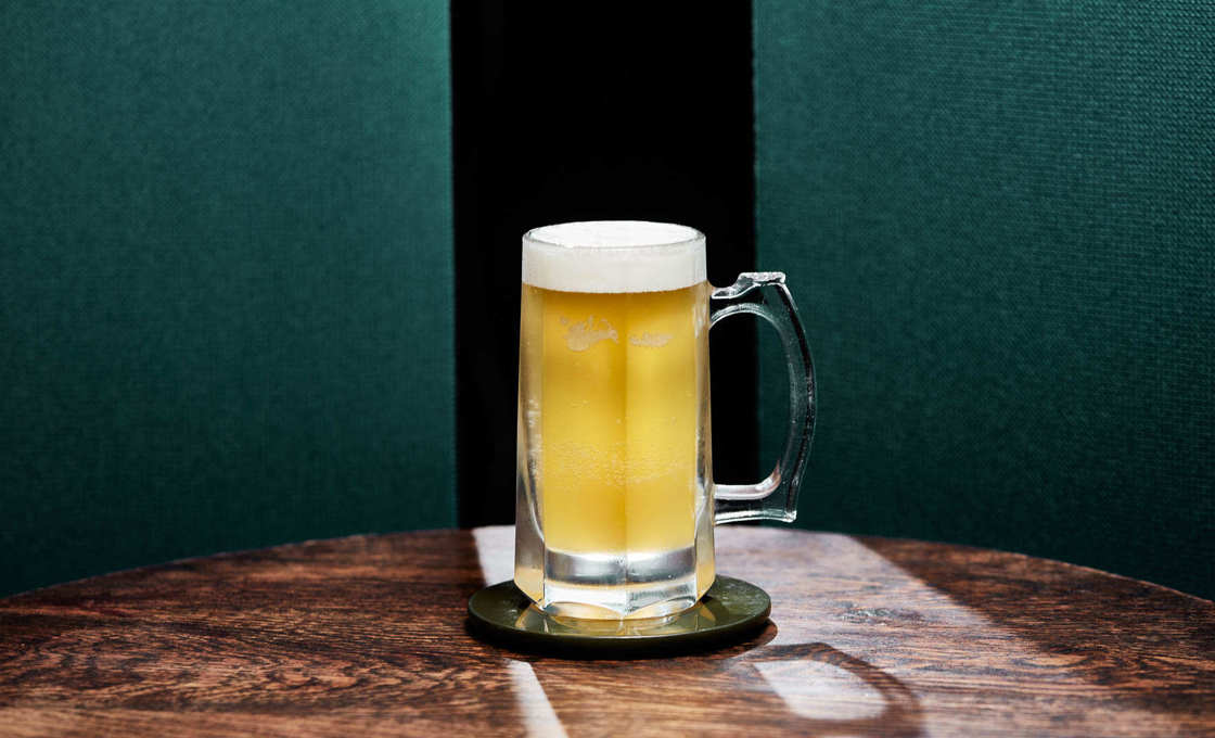 A glass of Lager Tropicale on a wooden table